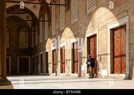 Un homme debout dans la lumière du soleil tôt le matin sur les murs de la cour intérieure de la Mosquée Bleue à Sultanahmet, Istanbul Banque D'Images