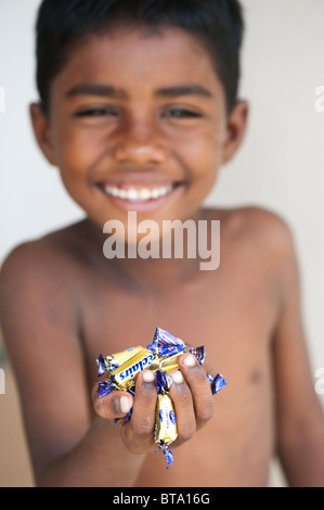 Jeune Indien boy holding bonbons dans sa main. L'Inde. Selective focus Banque D'Images