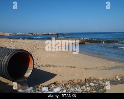 Un tuyau d'égout en vide le contenu sur une plage Méditerranéenne à Tripoli, Libye Banque D'Images