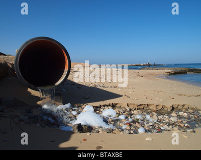 Un tuyau d'égout en vide le contenu sur une plage Méditerranéenne à Tripoli, Libye Banque D'Images