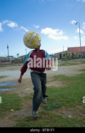 Un garçon jouant au football dans le canton de Zola à Somerset West, près de Cape Town, Afrique du Sud. Banque D'Images