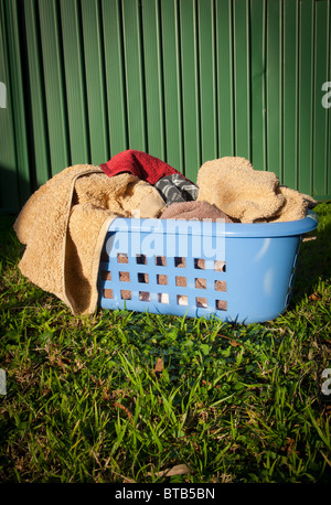 Panier à linge bleu rempli de serviettes est assis sur une pelouse à l'extérieur Banque D'Images