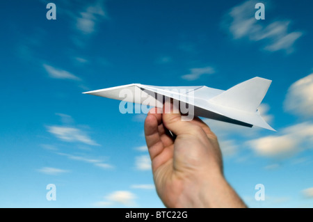 Mans hand holding paper aeroplane avec fond de ciel bleu Banque D'Images