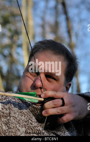 Homme de tir avec arc et flèche en forêt, Stockholms Lan, Suède Banque D'Images