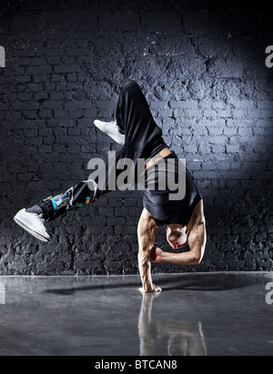 Jeune homme fort break dance. Sur le mur sombre arrière-plan. Banque D'Images