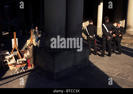 Les peintures de l'artiste pour les touristes et les officiers carabiniers patrouille dans Florence Piazza degli Uffizi. Banque D'Images