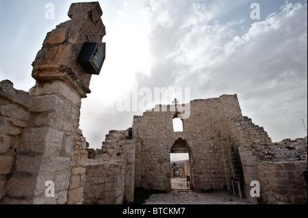 Le soleil brille à travers les nuages sur les ruines d'une ancienne église dans la ville cisjordanienne de Taybeh. Banque D'Images