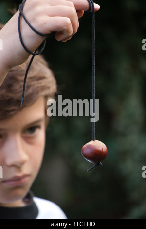 Un garçon est titulaire d'un conker sur une chaîne de caractères pour le jeu conker Banque D'Images