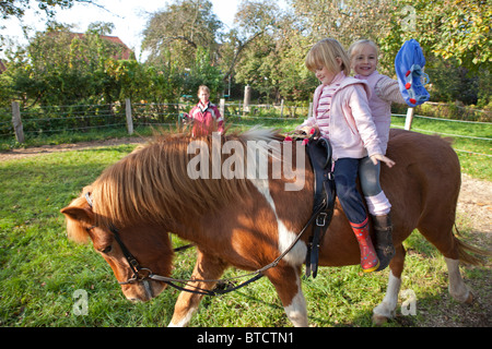 Deux petites filles équitation poney ensemble dirigés par leur professeur d'équitation Banque D'Images
