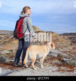 Randonnée femme avec son chien Labrador Retriever jaune, surplombant le Canyon voleur de chevaux, Badlands, Drumheller, Alberta, Canada. Banque D'Images