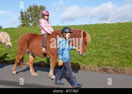 Petit Poney girl riding a dirigé par une autre fille Banque D'Images