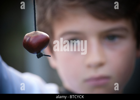 Un garçon est titulaire d'un conker sur une chaîne de caractères pour le jeu conker Banque D'Images