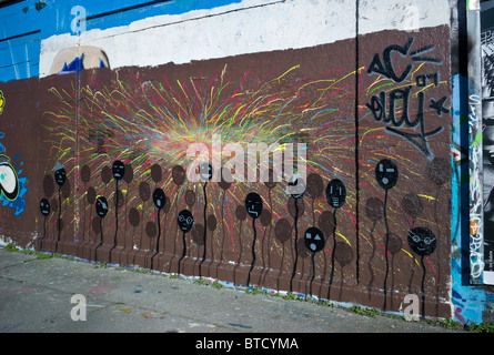 Mur public montrant sur un graffiti couverts fond brun brun noir de ballons avec des visages et de l'explosion de couleurs, Munich, Allemagne Banque D'Images