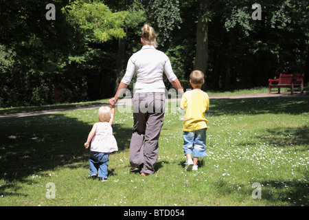 Maman et deux enfants qui s'éloignent d'appareil photo. Banque D'Images