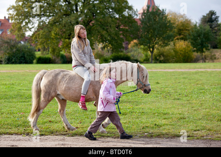 Teenage girl riding a pony conduit par une petite fille Banque D'Images