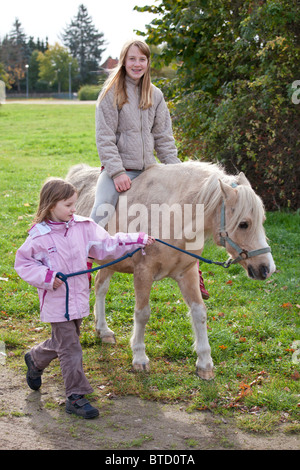 Teenage girl riding a pony conduit par une petite fille Banque D'Images