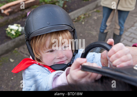 Petite fille essayant de monter sur un poney Banque D'Images