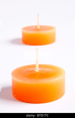 Tealight candles in bright orange contre un fond uni Banque D'Images