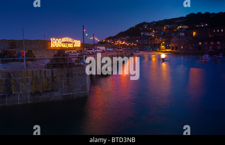 Nuit qui tombe sur le balancement des bateaux sur la marée dans le port de pêche dans le vieux village de Mousehole [Cornwall] Banque D'Images