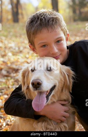 Portrait of happy Young boy hugging son golden retriever dog Banque D'Images