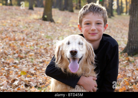 Portrait of happy Young boy hugging son golden retriever dog Banque D'Images