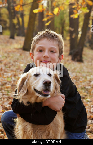 Portrait of happy Young boy hugging son golden retriever dog Banque D'Images