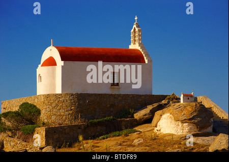 L'un des centaines de chapelles traditionnelles au toit rouge sur Mykonos, avec un avion à l'atterrissage, Islads Cyclades, Grèce Banque D'Images
