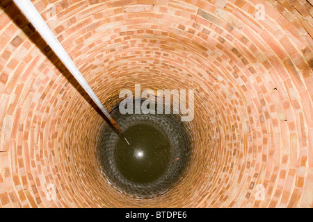 Intérieur de l'eau bordée d'une brique bien avec tuyau d'acier Banque D'Images