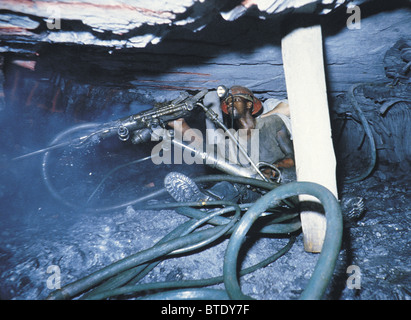 Le forage sous terre dans une mine d'montrant les flexibles haute pression et des conditions de travail exiguës. Banque D'Images