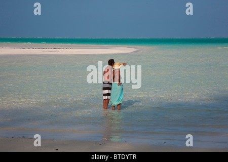 Couple dans l'eau peu profonde sur la plage de l'île tropicale (modèle de Mnemba) Parution Banque D'Images