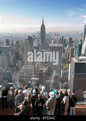 Les touristes à la recherche à l'Empire State Building du haut de la roche plate-forme d'observation au Rockefeller Center de Manhattan New York Banque D'Images