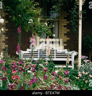 Nicotiana rose et digitales en frontière en face de véranda avec ornements de style Lutyens blanc banc de jardin Banque D'Images