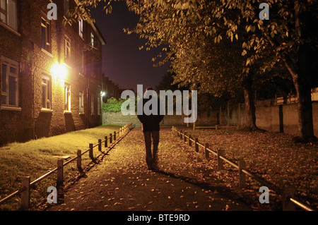 Homme marchant le long lane la nuit Banque D'Images