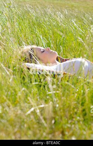 Jeune femme la sieste dans l'herbe haute Banque D'Images