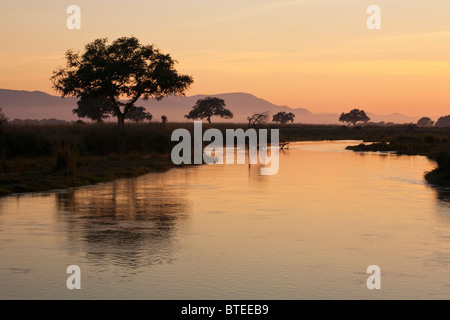 Coucher de soleil avec en premier plan la rivière Zambèze et la montagne et les arbres en arrière-plan Banque D'Images