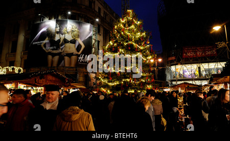 La foule se rassembler autour d'elle la petite vente stalles en bois de marchandises de Noël au Marché de Noël de la place Vorosmarty, Budapest, Hongrie Banque D'Images