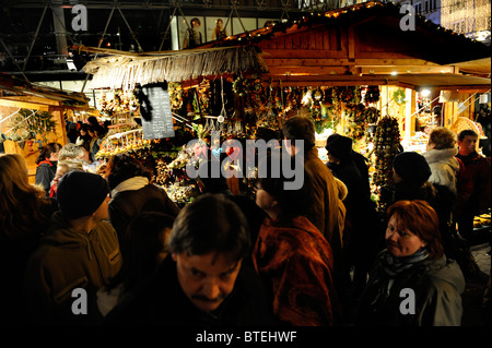 La foule se rassembler autour d'elle la petite vente stalles en bois de marchandises de Noël au Marché de Noël de la place Vorosmarty, Budapest, Hongrie Banque D'Images