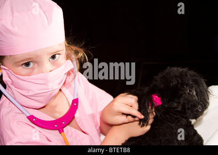 Jeune fille habillé comme un médecin ou un vétérinaire en aidant les petits chiens caniche rose Banque D'Images