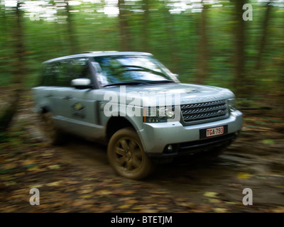 Range Rover roulant le long d'un chemin très boueux dans la forêt au domaine d'Arthey estate, Belgique. with motion blur Banque D'Images