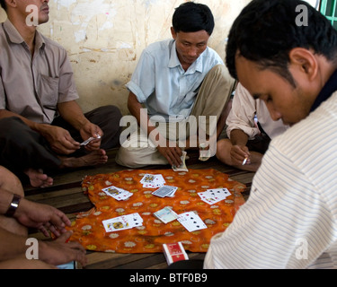 Un groupe d'hommes sont le jeu et les cartes à jouer sur une rue de Kampong Cham, au Cambodge. Banque D'Images