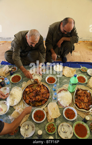 Un groupe de combattants kurdes des forces de défense populaires HPG, l'aile militaire du PKK du Parti des travailleurs du Kurdistan, mangeant de la nourriture traditionnelle kurde dans une maison sûre dans un village rural dans les montagnes de Qandil, une zone montagneuse près de la frontière avec l'Iran en Irak Banque D'Images