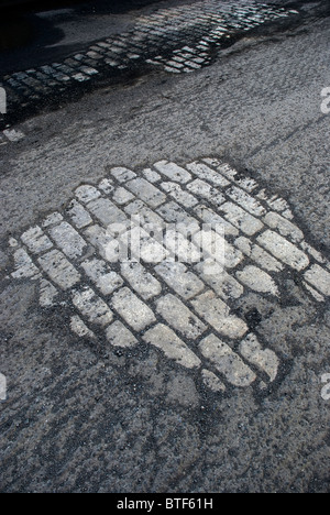 La fondation en pierre apparente sous route macadam effilochés resurfaçage attend Banque D'Images