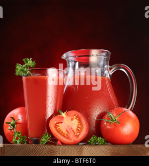 Still Life : tomates, verseuse en verre et plein de jus de tomates fraîches sur la table en bois. Banque D'Images