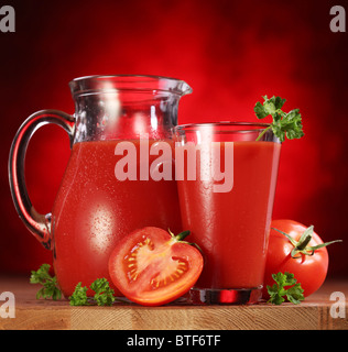 Still Life : tomates, verseuse en verre et plein de jus de tomates fraîches sur la table en bois. Banque D'Images