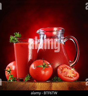 Still Life : tomates, verseuse en verre et plein de jus de tomates fraîches sur la table en bois. Banque D'Images