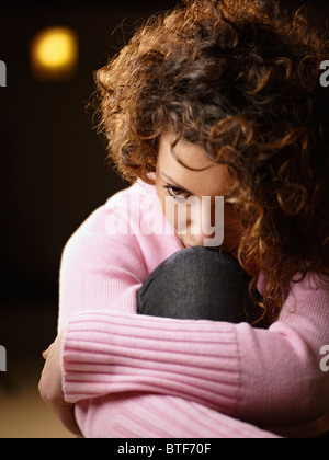 Sad woman sitting on floor holding genoux Banque D'Images