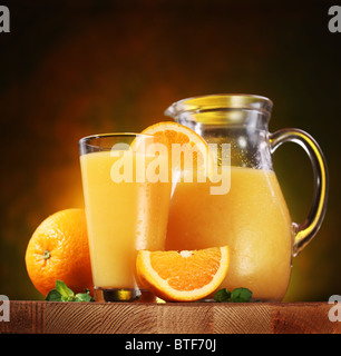 Still Life : oranges, verre de jus et jus de plein pot sur une table en bois. Banque D'Images