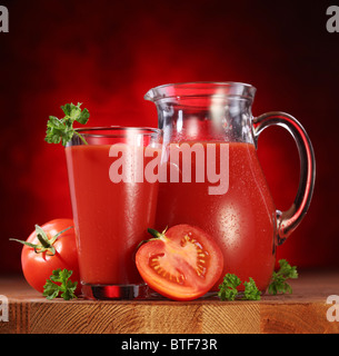 Still Life : tomates, verseuse en verre et plein de jus de tomates fraîches sur la table en bois. Banque D'Images