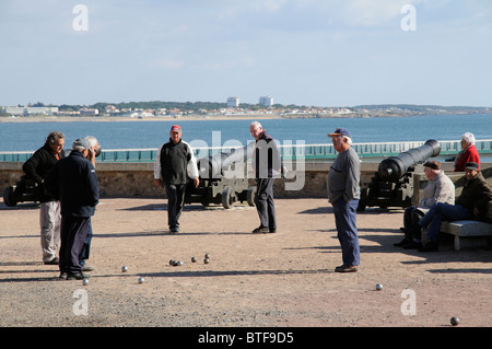 Les hommes jouant pétanque sur le front de mer de la Chaume avec une toile de fond des Sables d' Olonne en Vendée de France Banque D'Images