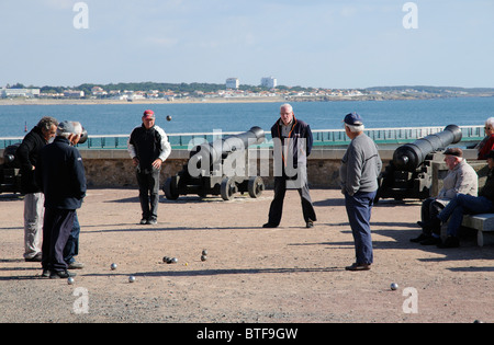 Les hommes jouant pétanque sur le front de mer de la Chaume avec une toile de fond des Sables d' Olonne en Vendée de France Banque D'Images